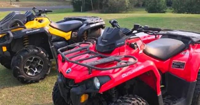 Close-up red ATV on grassy field showing front rack and tires