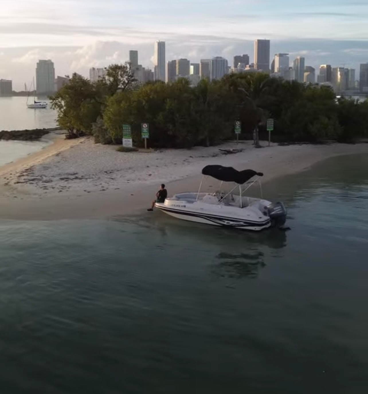 Beached powerboat by mangrove islet with Miami skyline backdrop