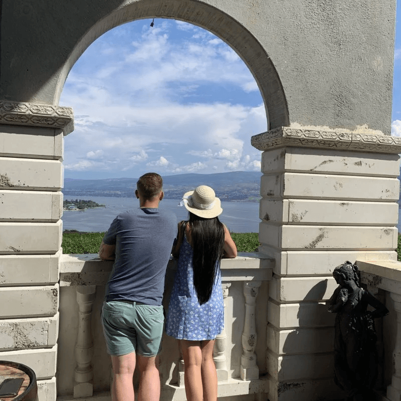 Couple viewing vineyard and lake panorama through stone arch