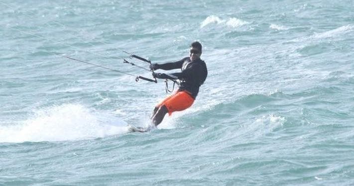 Kitesurfer carving across choppy Pacific waters off Maui coast
