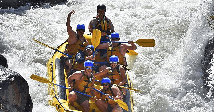 Rafting team navigating powerful whitewater canyon rapids