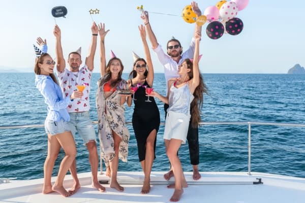Group celebrating on yacht bow with ocean views and balloons