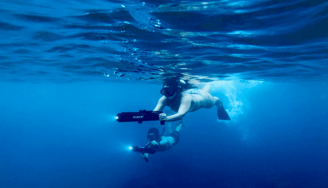 Underwater diver riding DPV (scooter) over deep blue ocean seascape
