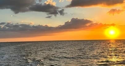 Sunset cruise over Gulf waters with golden horizon view