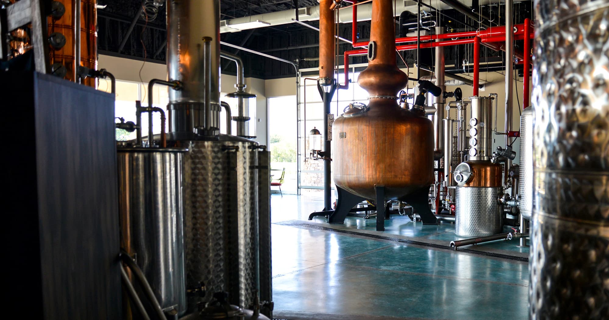 Copper distillery stills in industrial tasting room, craft spirits tour