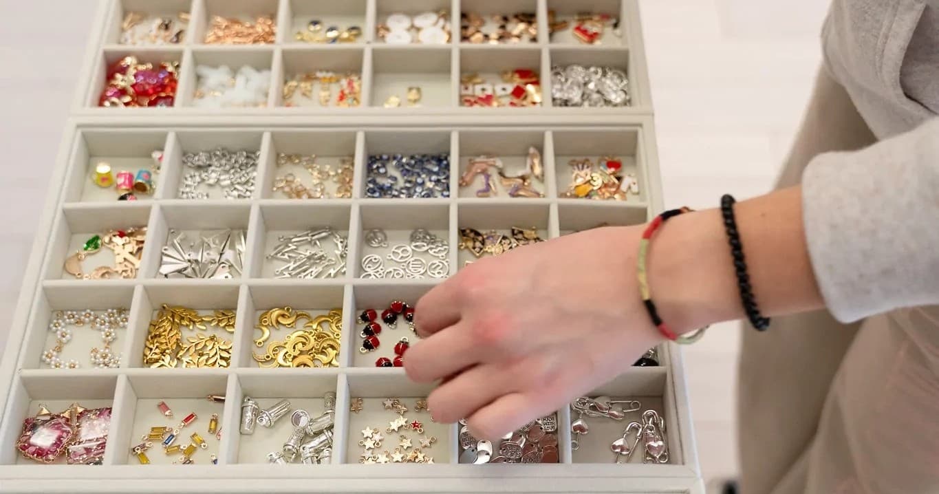 Selecting charms from compartment tray in indoor bead workshop