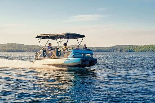 Pontoon boat cruising on calm lake with forested shoreline