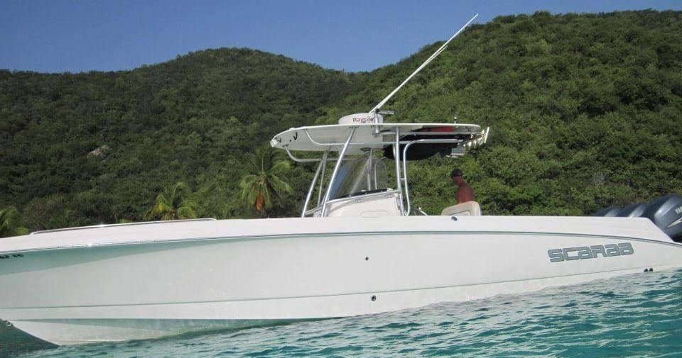 White center-console boat anchored near lush hillside in tropical bay