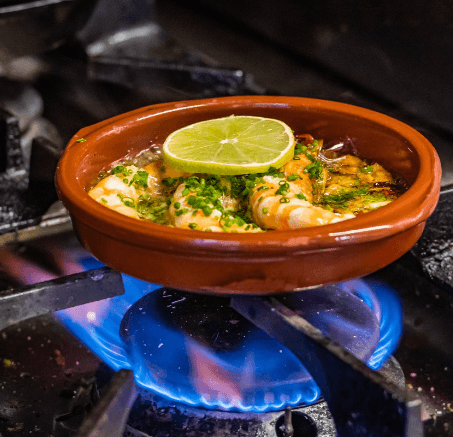 Sizzling garlic prawns cooked over flame in restaurant kitchen