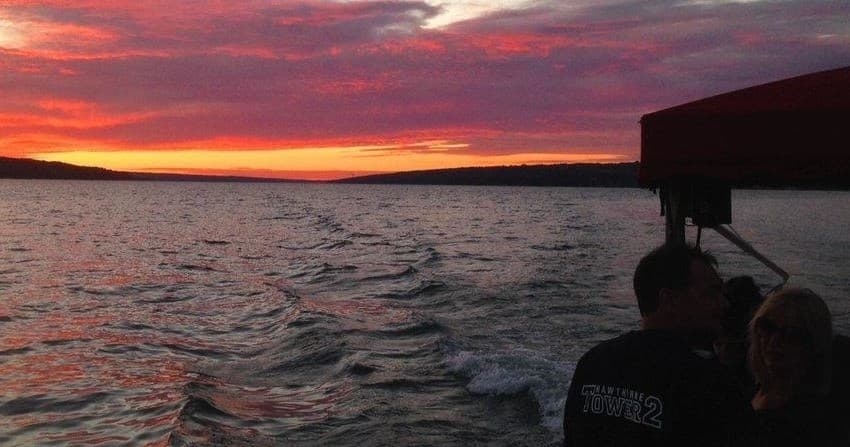 Sunset cruise over Cayuga Lake with boat silhouette
