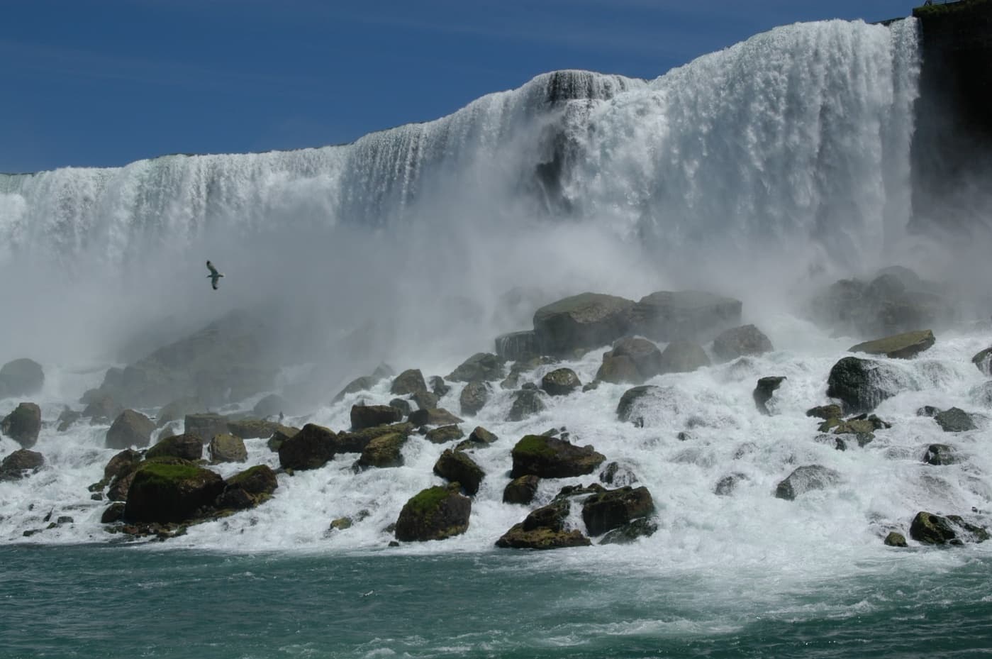 Visitors viewing cascading Niagara Falls and mist over rocky rapids
