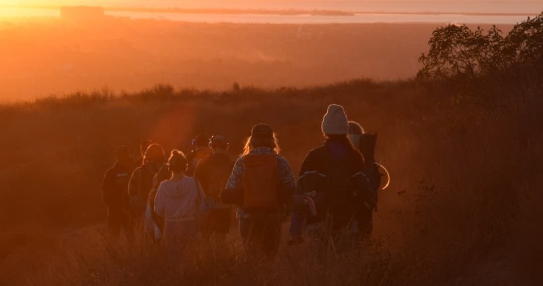 Group hiking at sunset on coastal bluff trail
