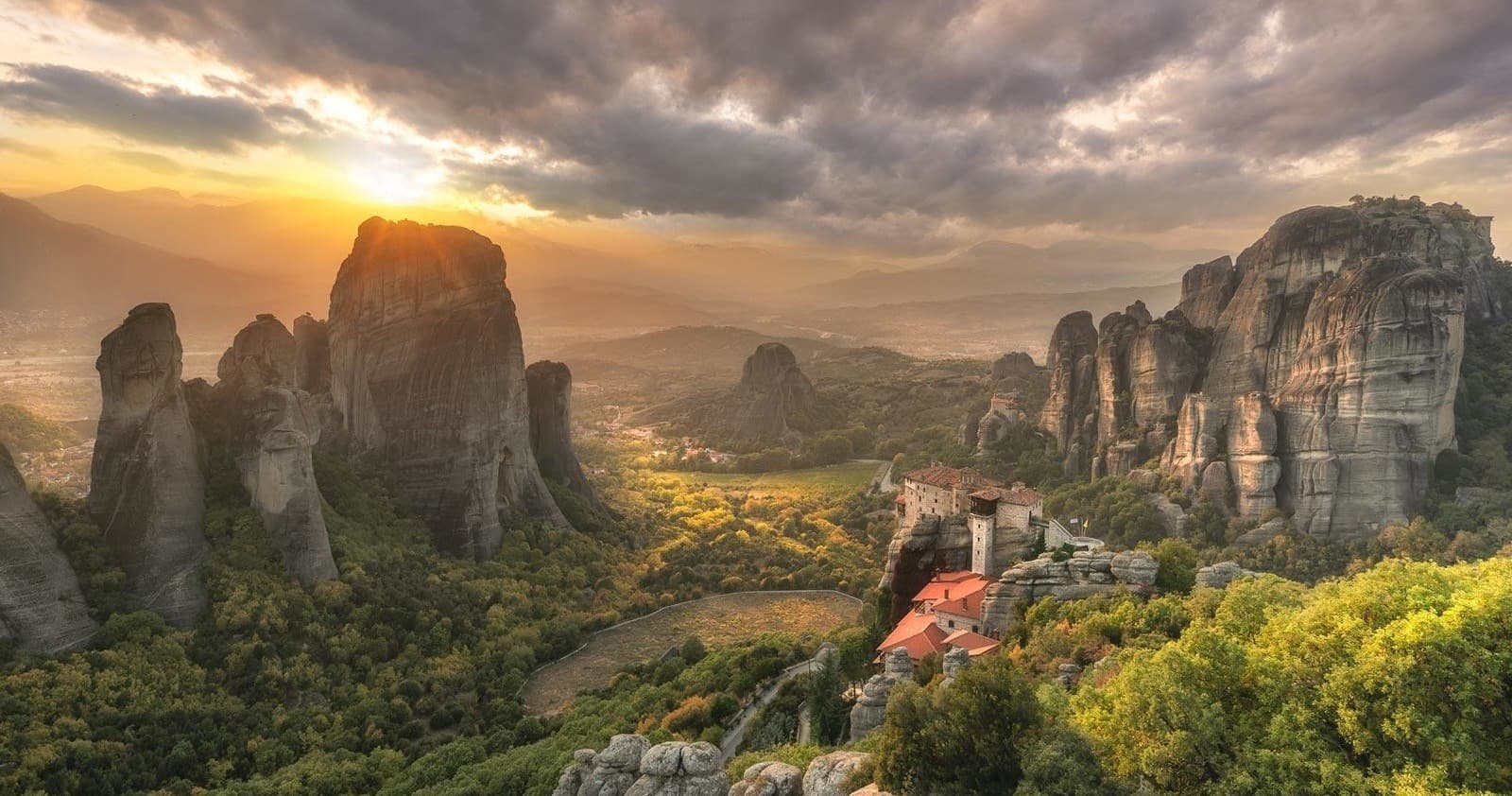 Sunrise over Meteora rock formations and cliffside monastery