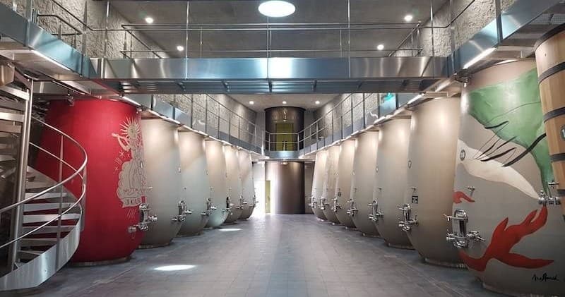 Winery fermentation room with painted concrete vats and spiral stairs