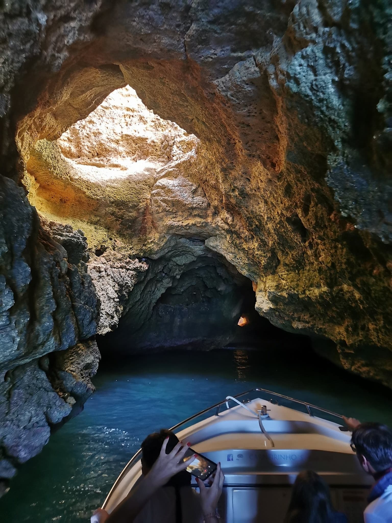 Small boat navigating into dramatic sea cave interior