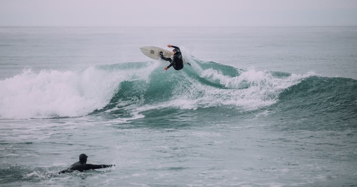 Surfer launching aerial maneuver over breaking ocean wave