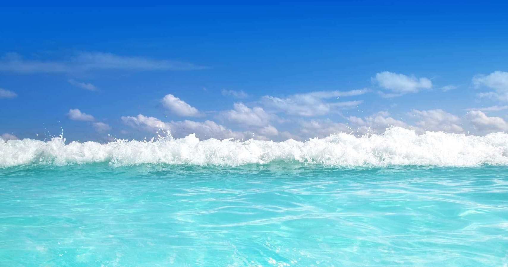 Turquoise ocean waves breaking under blue sky, Maui coast