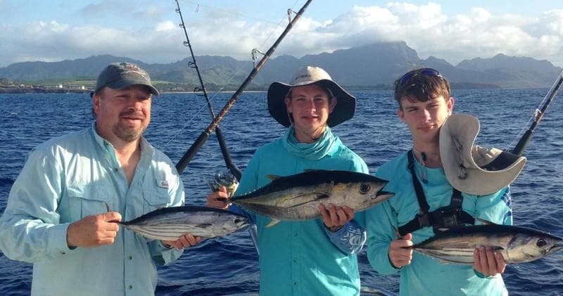Anglers holding tuna on sportfishing boat off Kauai coast