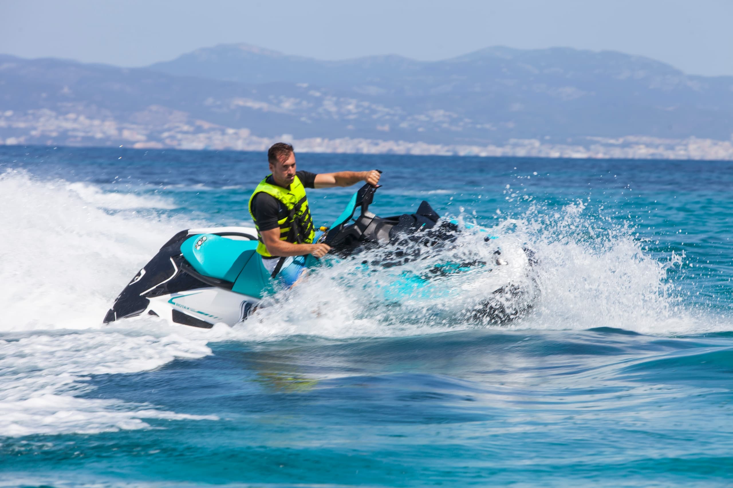 Solo rider carving waves on a turquoise sea near coastal mountains