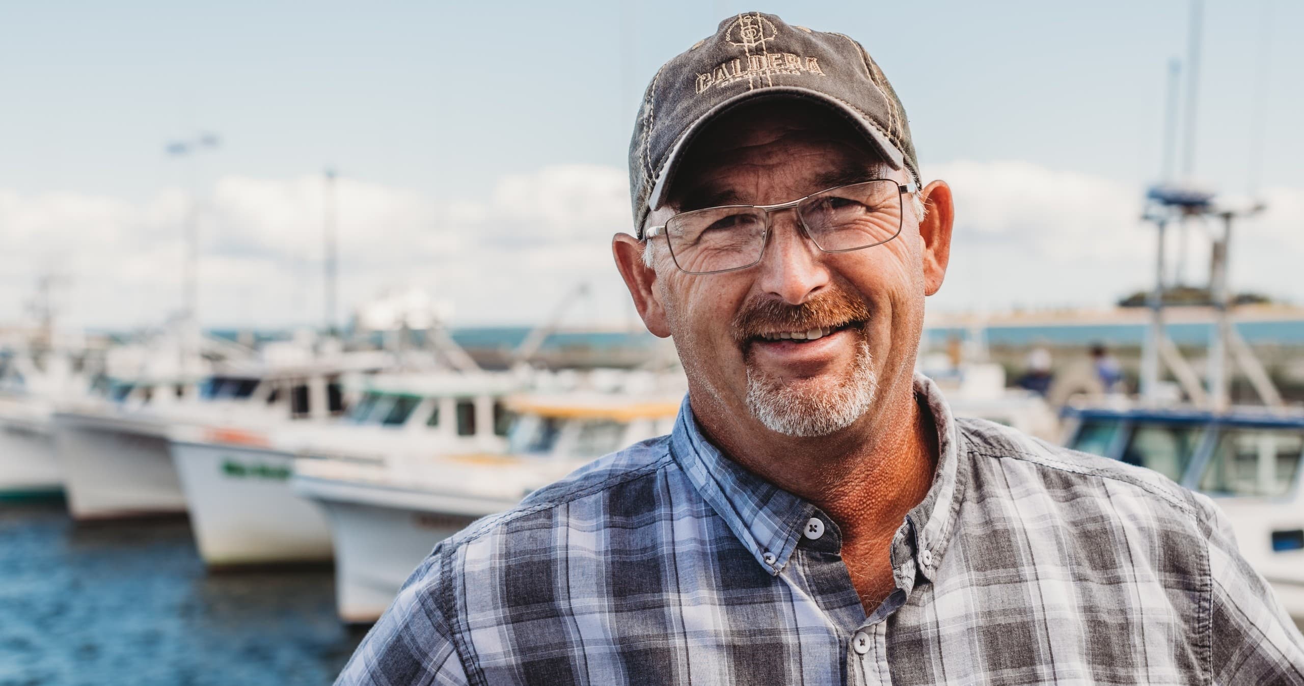 Smiling captain by marina boats, relaxed coastal fishing trip