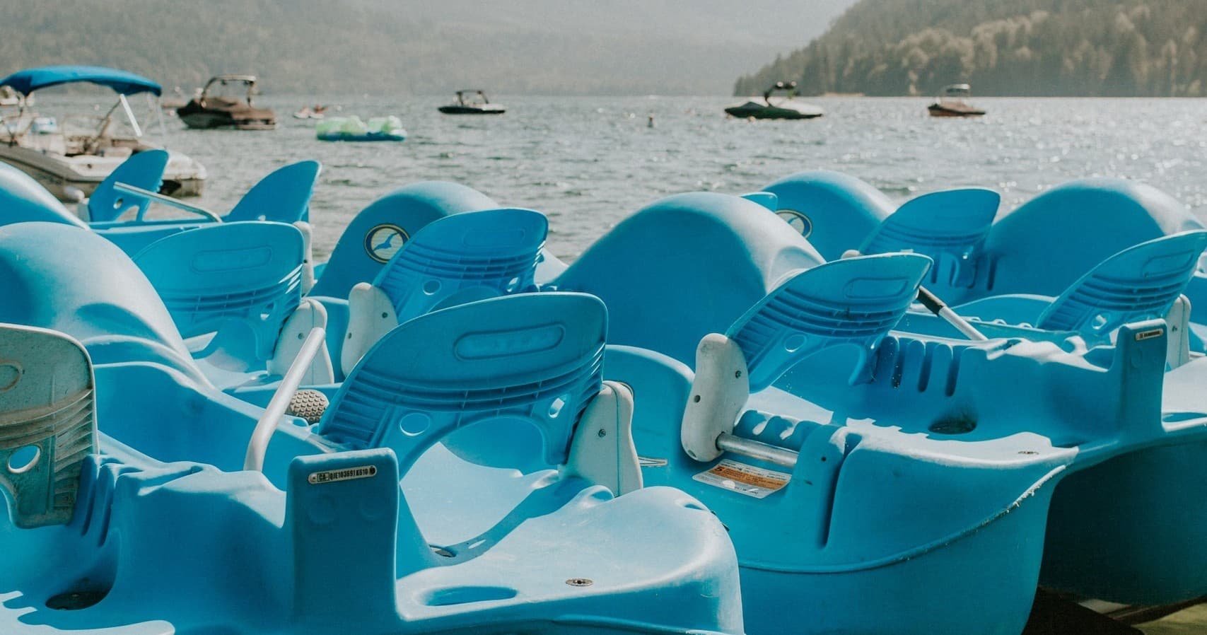 Cluster of blue pedal boats docked on lake shore for rentals