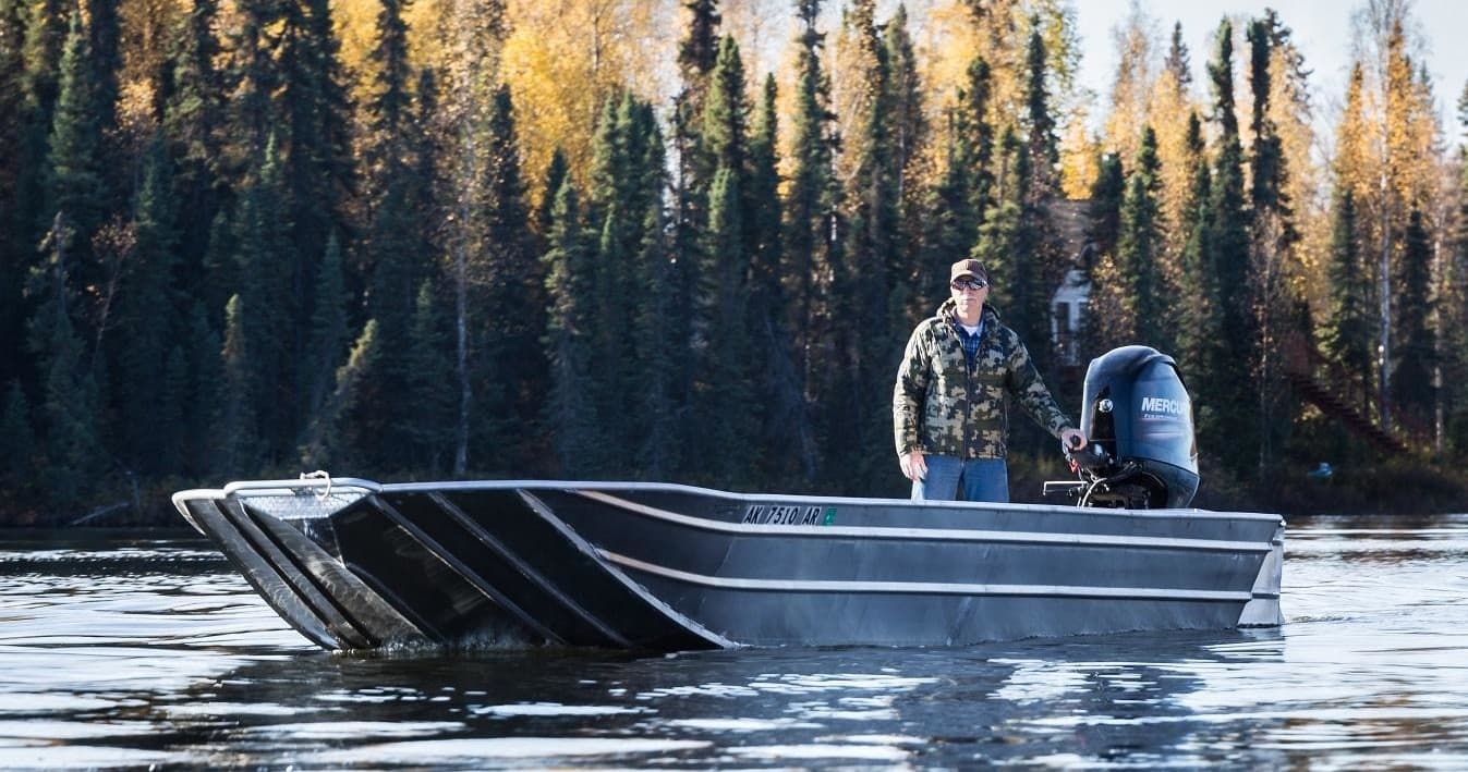 Aluminum fishing boat on calm Alaskan river with forested shore