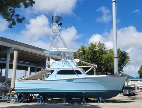 Sportfishing boat on stands in boatyard under blue sky
