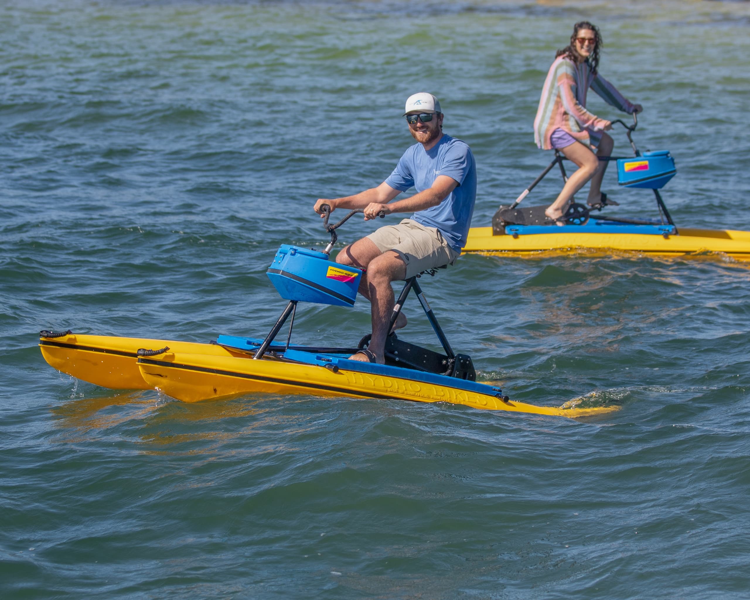 Two riders on pedal-powered water bikes across a bay