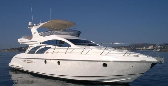White luxury motor yacht cruising coastal waters under clear sky
