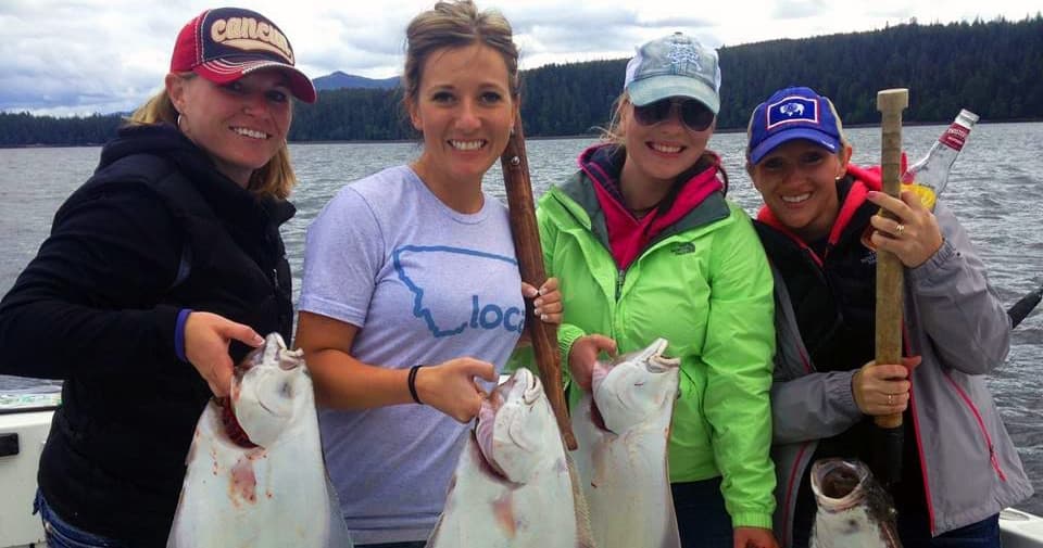 Women anglers holding halibut onboard fishing boat in Alaska