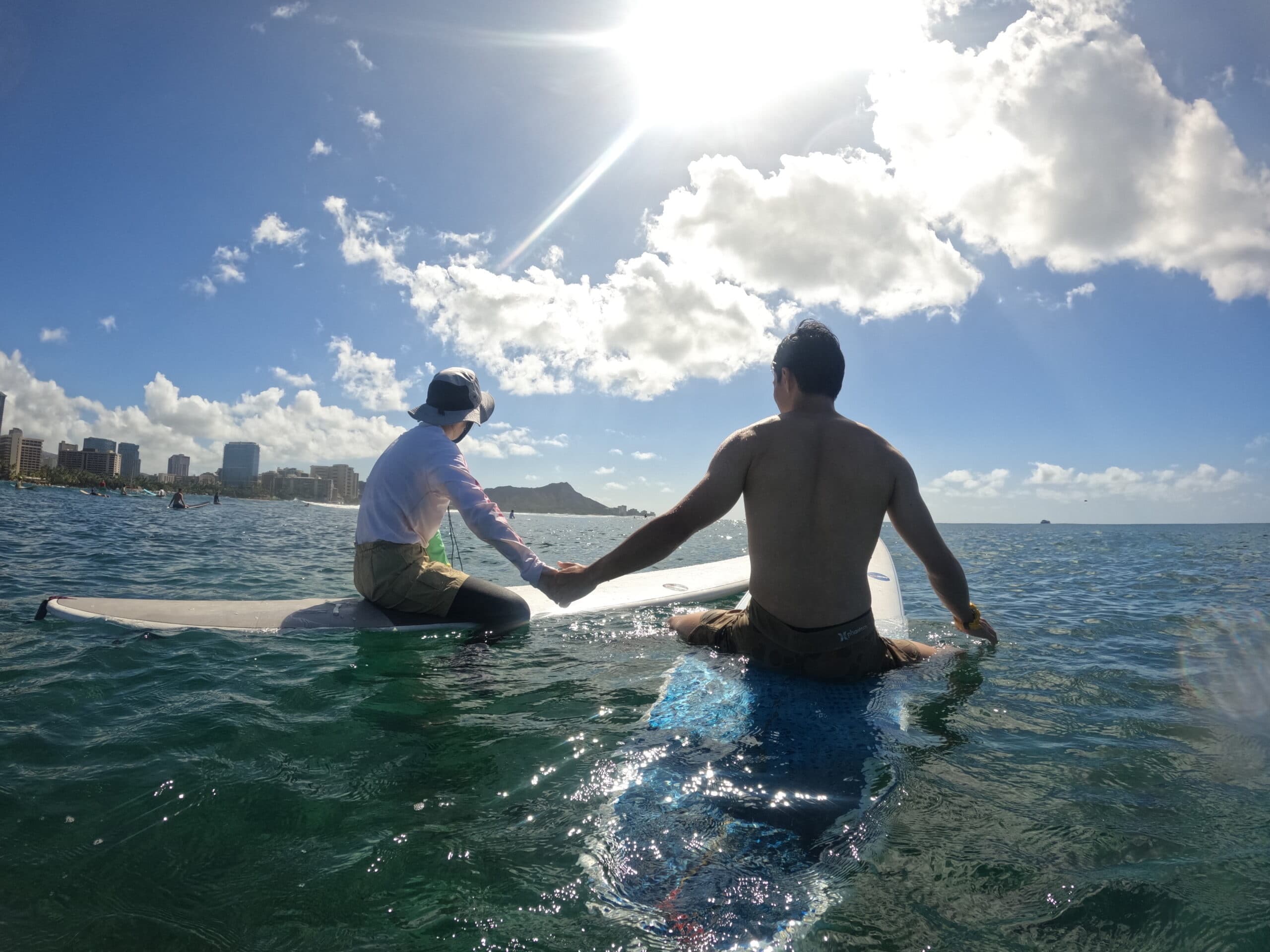 Two surfers sitting on surfboards in sunny ocean near shore