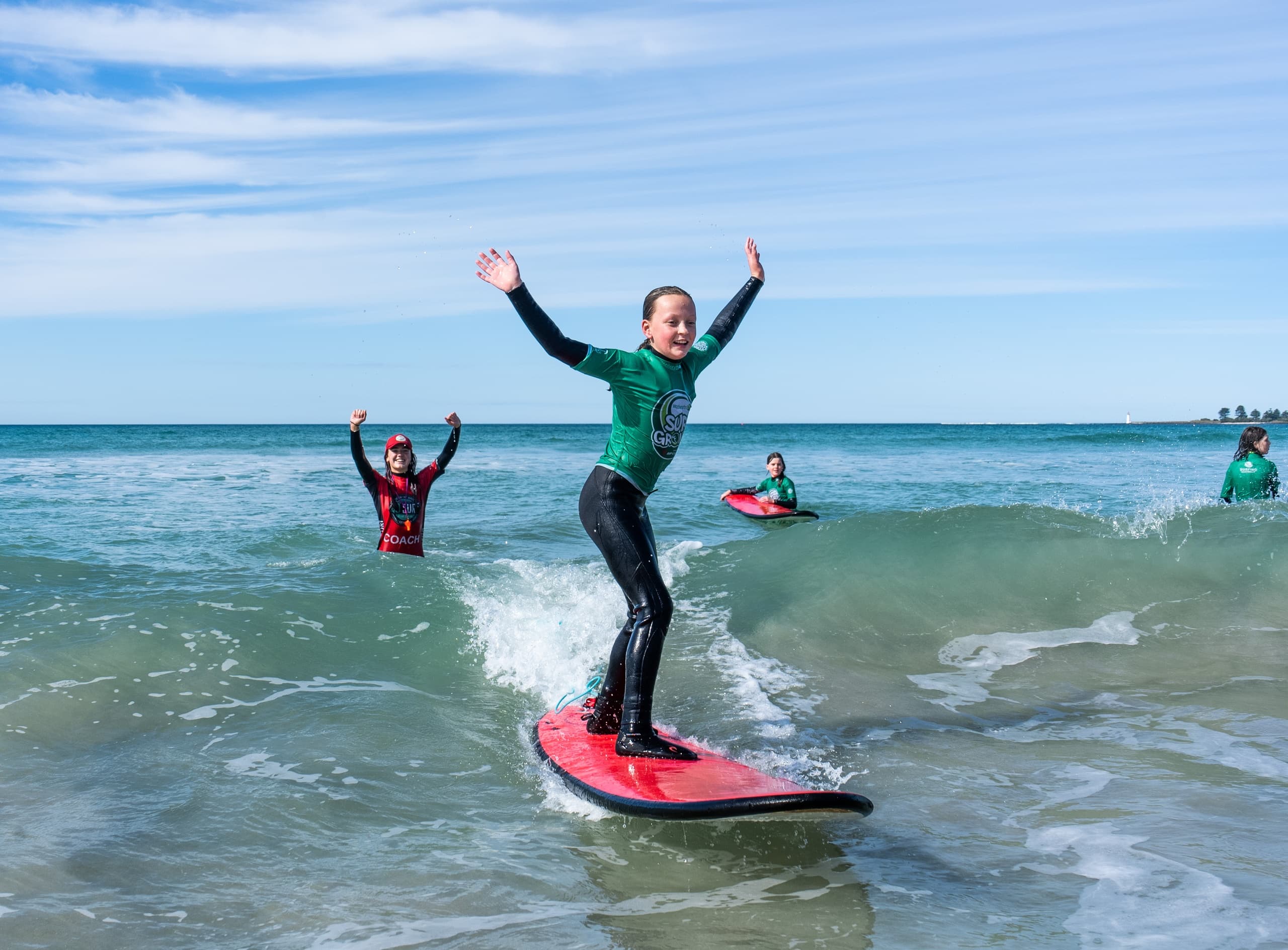 Surfer celebrating standing on board in calm coastal surf