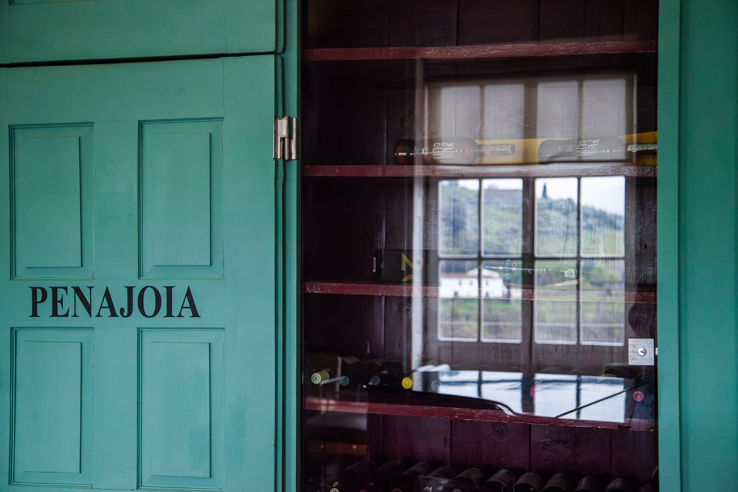 Green PENAJOIA storefront door and window reflecting Douro riverscape