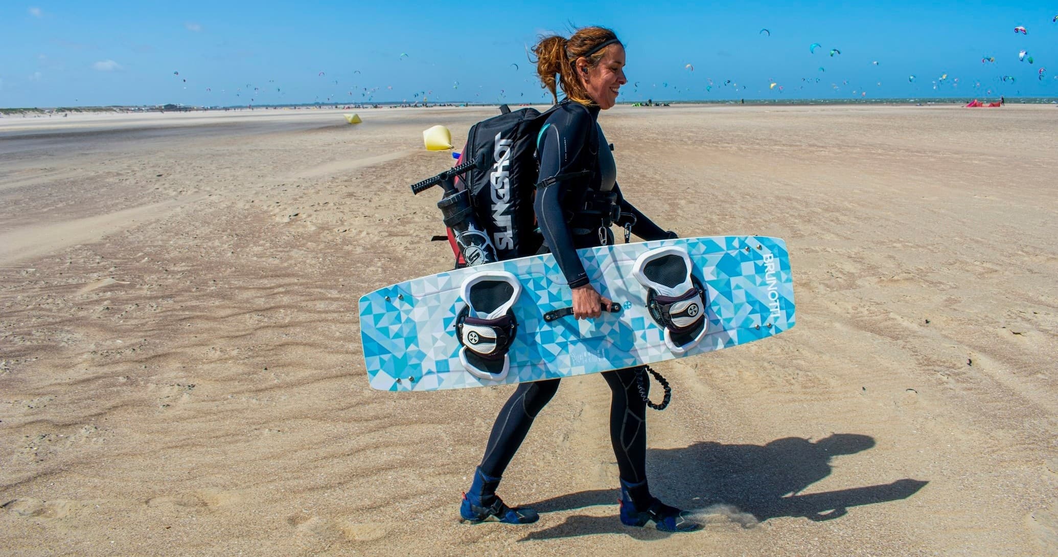 Kiteboarder walking on sandy beach toward the water