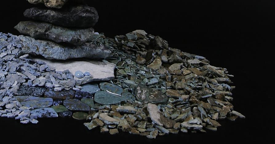 Closeup pile of raw turquoise stones displayed on dark backdrop