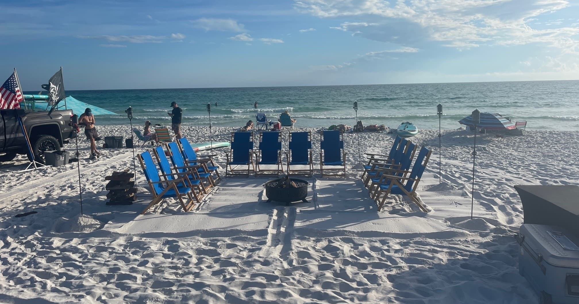 Beach bonfire circle with folding chairs on white sand beach