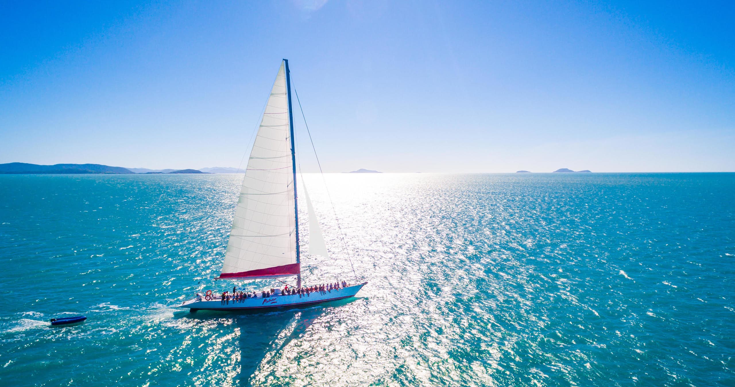 Single yacht sailing over clear turquoise ocean, sunny day