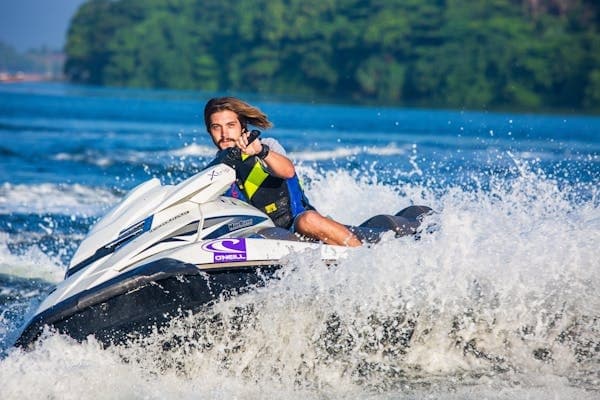 Jet ski rider cutting through lake waves near forested shoreline