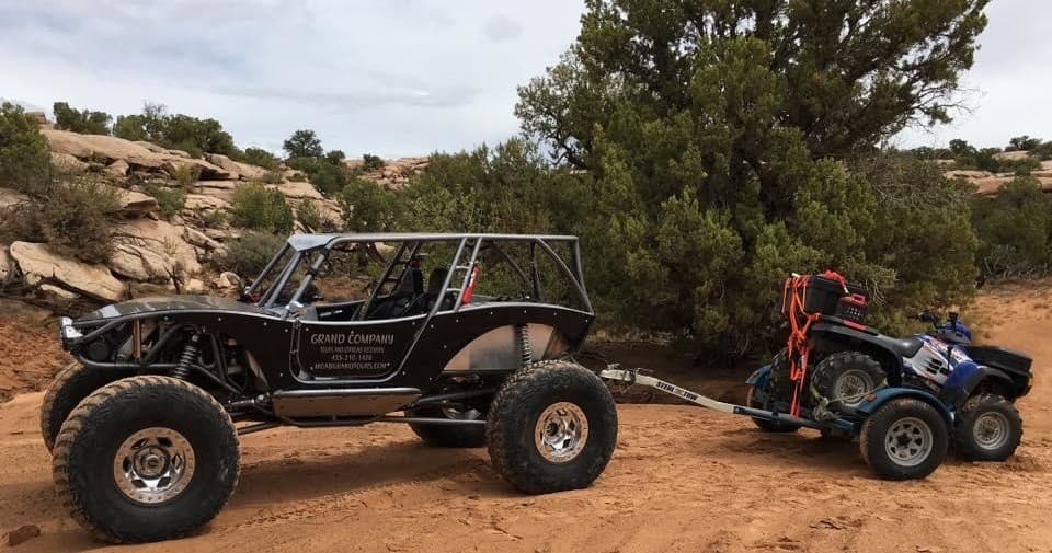 Off-road rock buggy towing UTV on Moab trails, adventure convoy