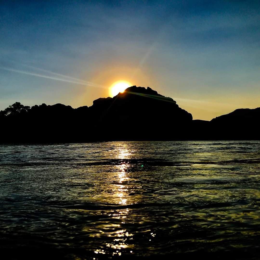 Sunset paddleboarding silhouette over calm lake and mountains
