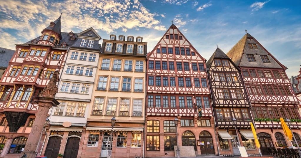 Walking past historic timber-framed buildings at Frankfurt Römerberg