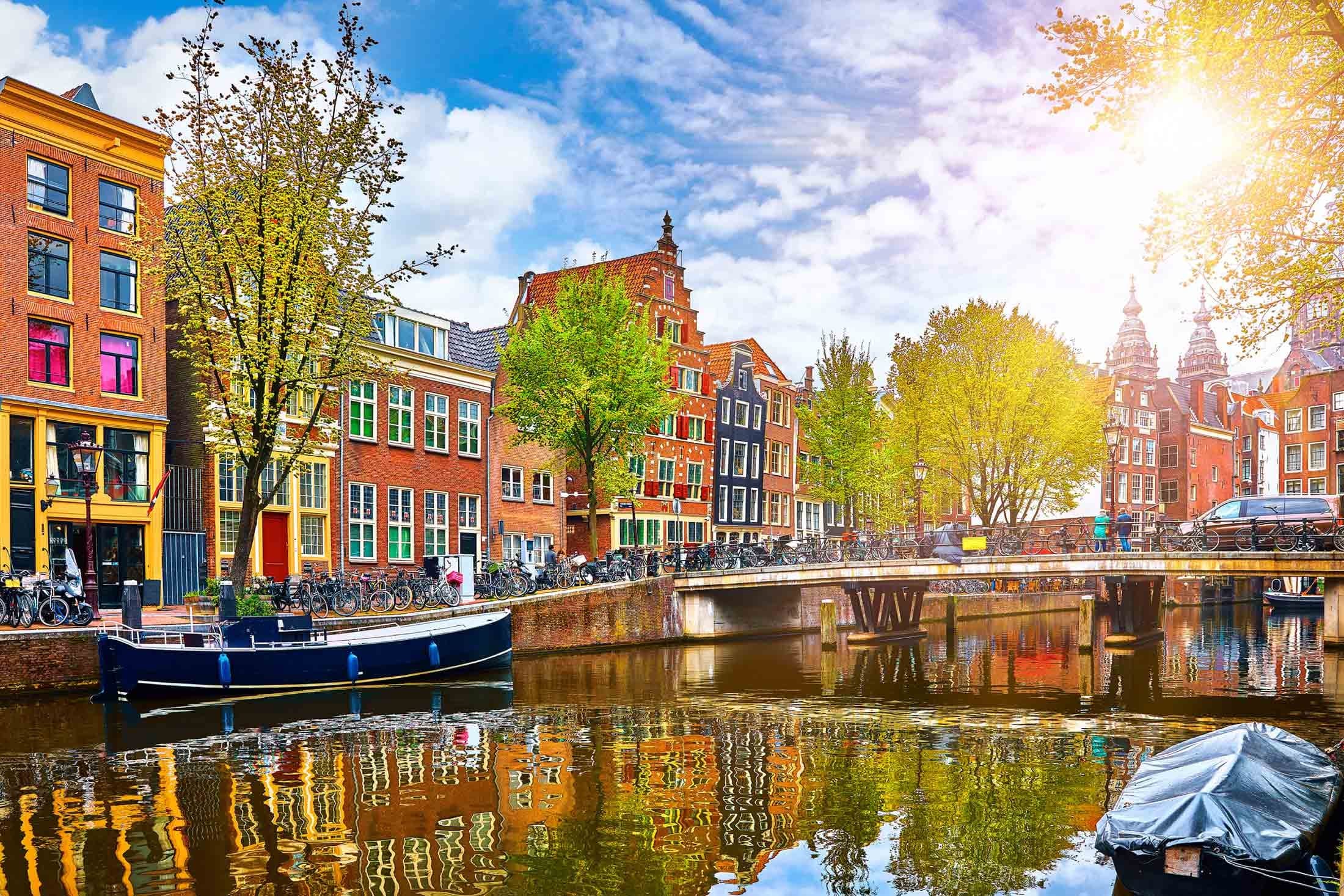 Vibrant Amsterdam canal houses lining boat-filled canal on sunny day
