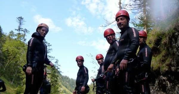 Canyoning group posing on river canyon rim under blue sky