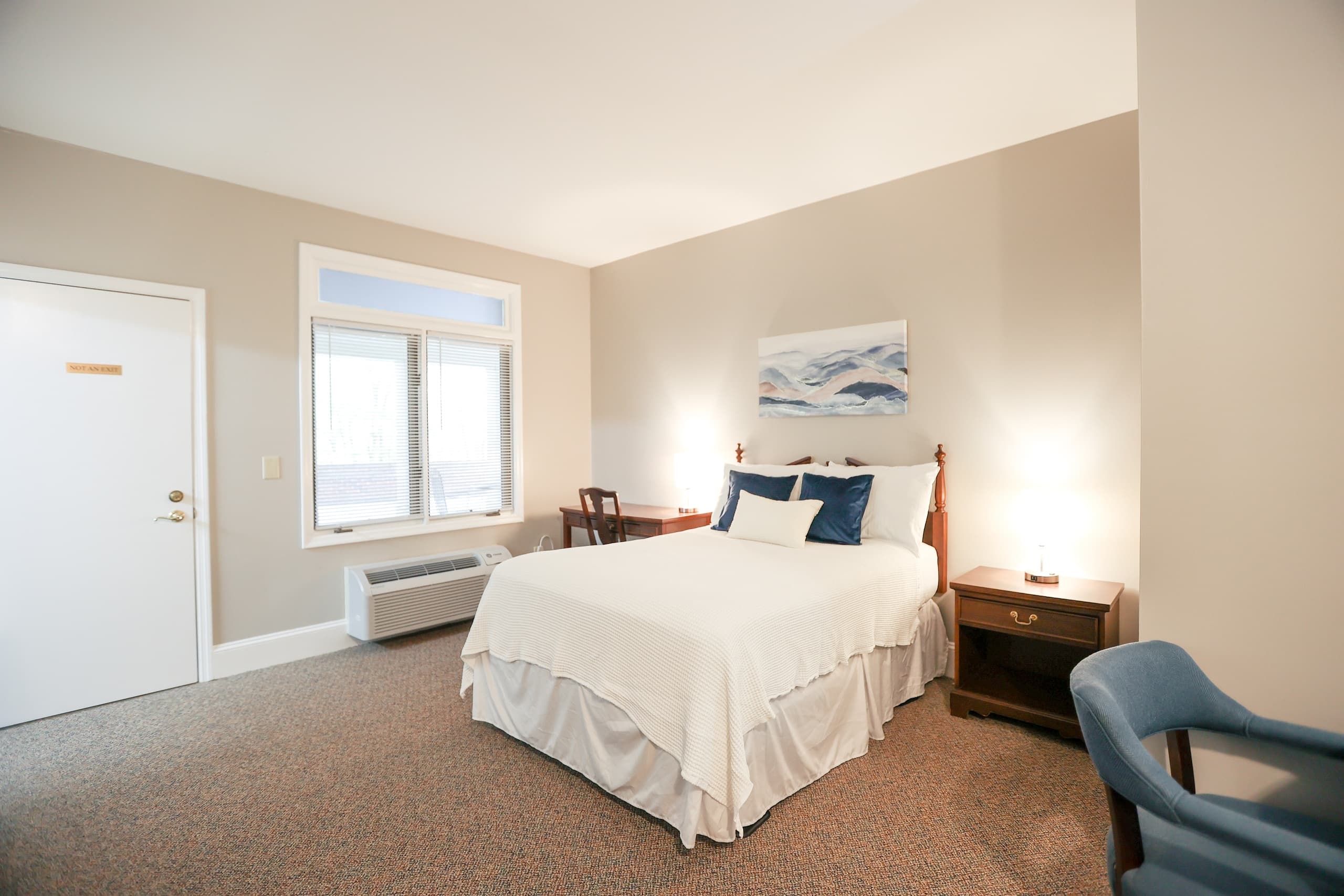 Well-lit hotel room with queen bed and table, comfortable stay