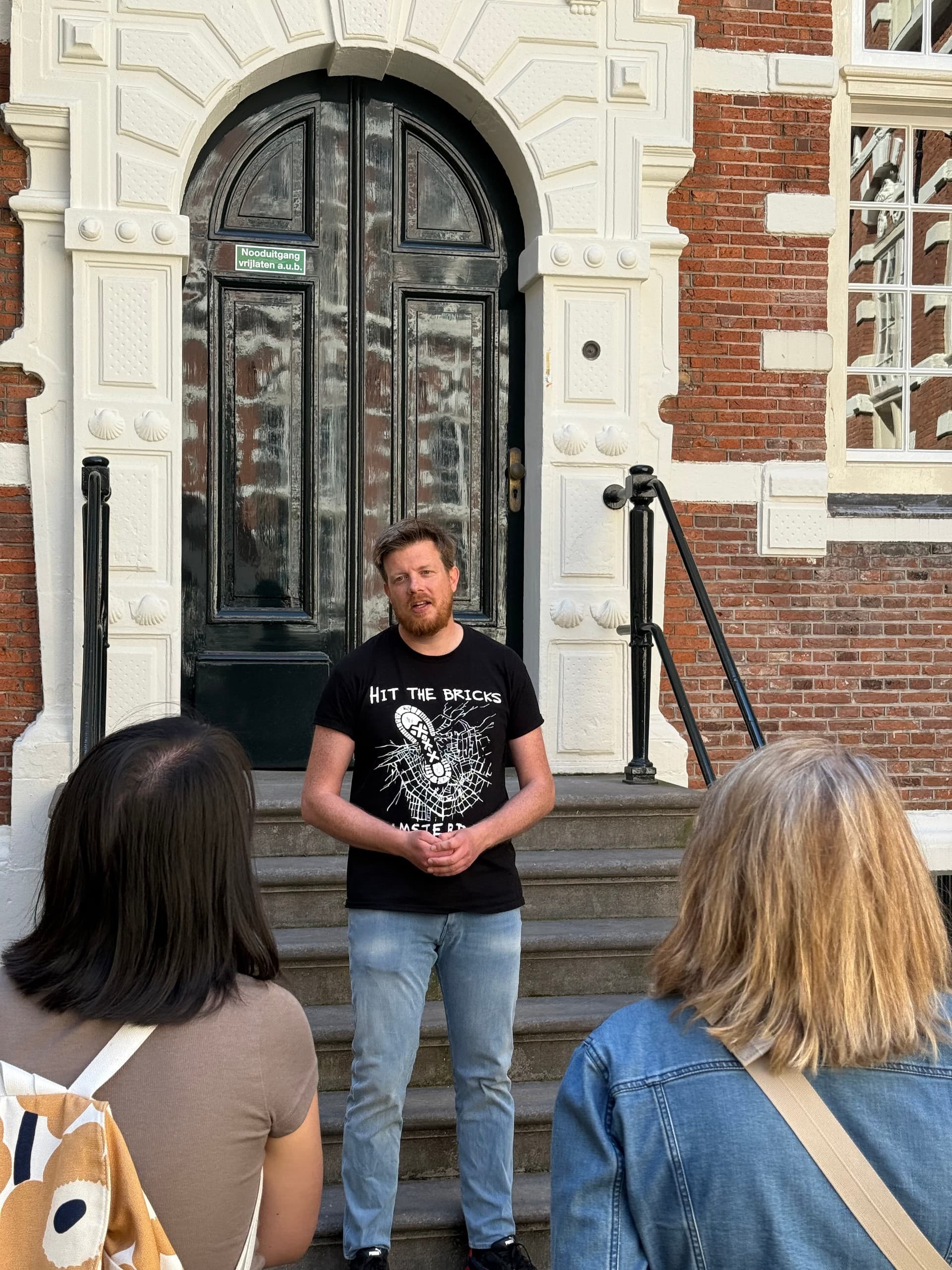 Tour guide speaking to group on steps of historic brick building