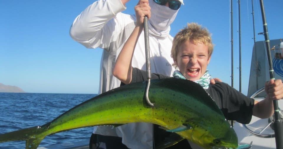 Child angler holding large dorado on deep-sea fishing charter