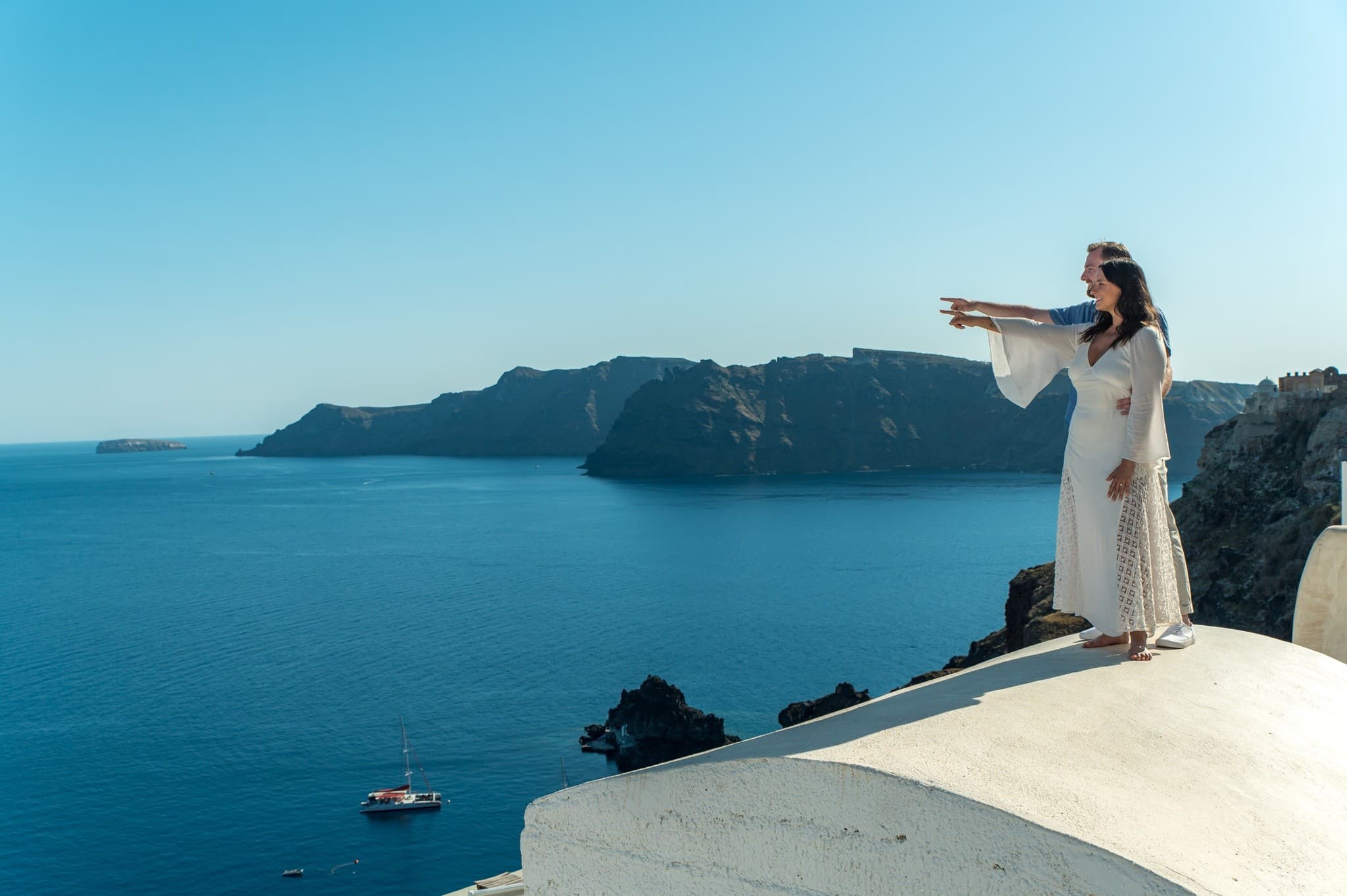 Couple posing by iconic blue-domed church in Oia Santorini