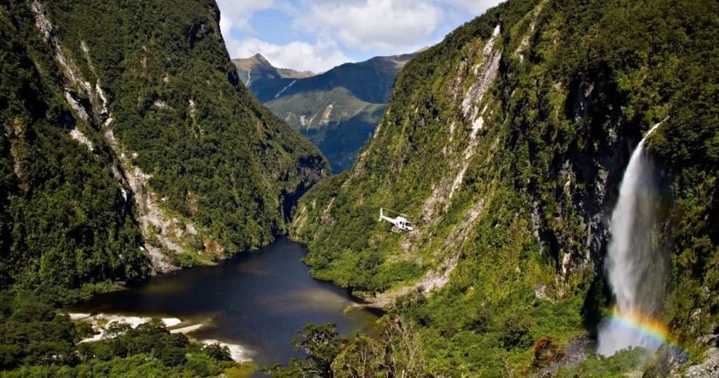 Lush valley waterfall and steep cliffs in alpine fjord