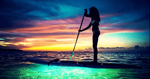 Solo paddleboarder at colorful sunset over tranquil sea