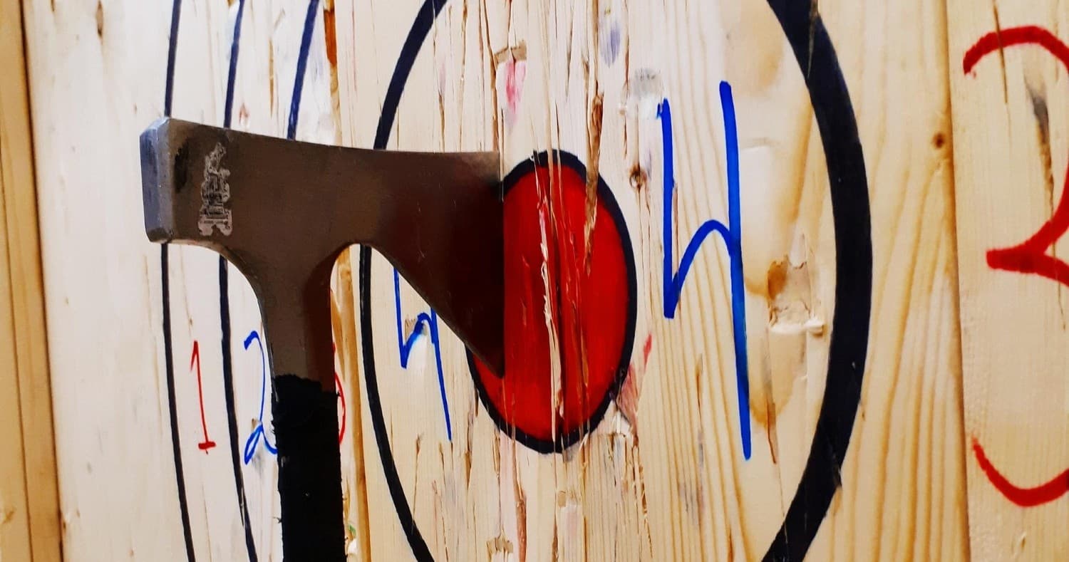 Axe embedded in wooden target at outdoor axe throwing lane